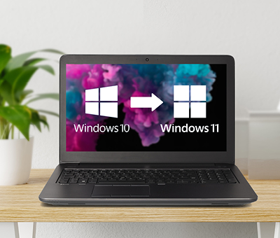die grafik zeigt ein geöffnetes notebook auf dessen desktop man sowohl das windows10 als auch das windows11 logo sieht. diese notebooks sind updatefähig