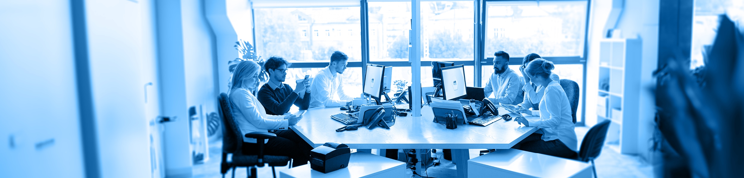 das Bild zeigt eine Büro-Situation mit mehreren Arbeitenden